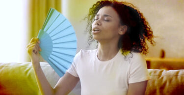 Woman fanning herself in a hot room